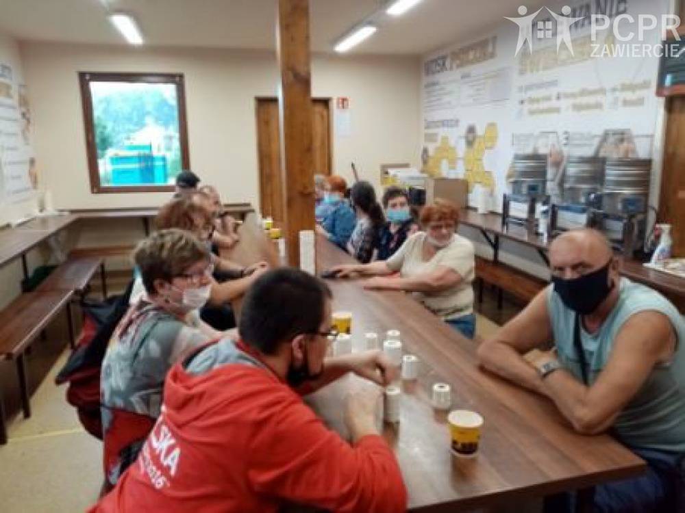 Zdjęcie: Grupa mężczyzn i kobiet siedząc przy stole ogląda produkty pszczelarskie